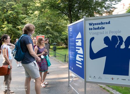 fotografia. wystawa Wyszehrad to ludzie na krakowskich plantach. ludzie oglądają plakaty ustawione w rzędzie.